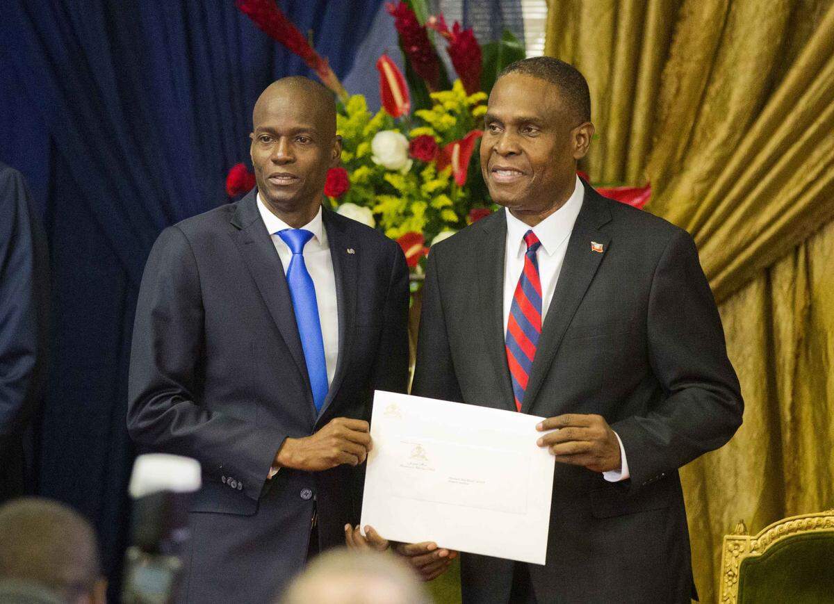 Jean Henry Céant, right, became Haiti’s prime minister in September, after the Lower Chamber of Deputies overwhelmingly voted in favor of his political program.  He poses for a picture with Haiti’s President Jovenel Moise as they hold up his appointment document at the National Palace in Port-au-Prince, Haiti.