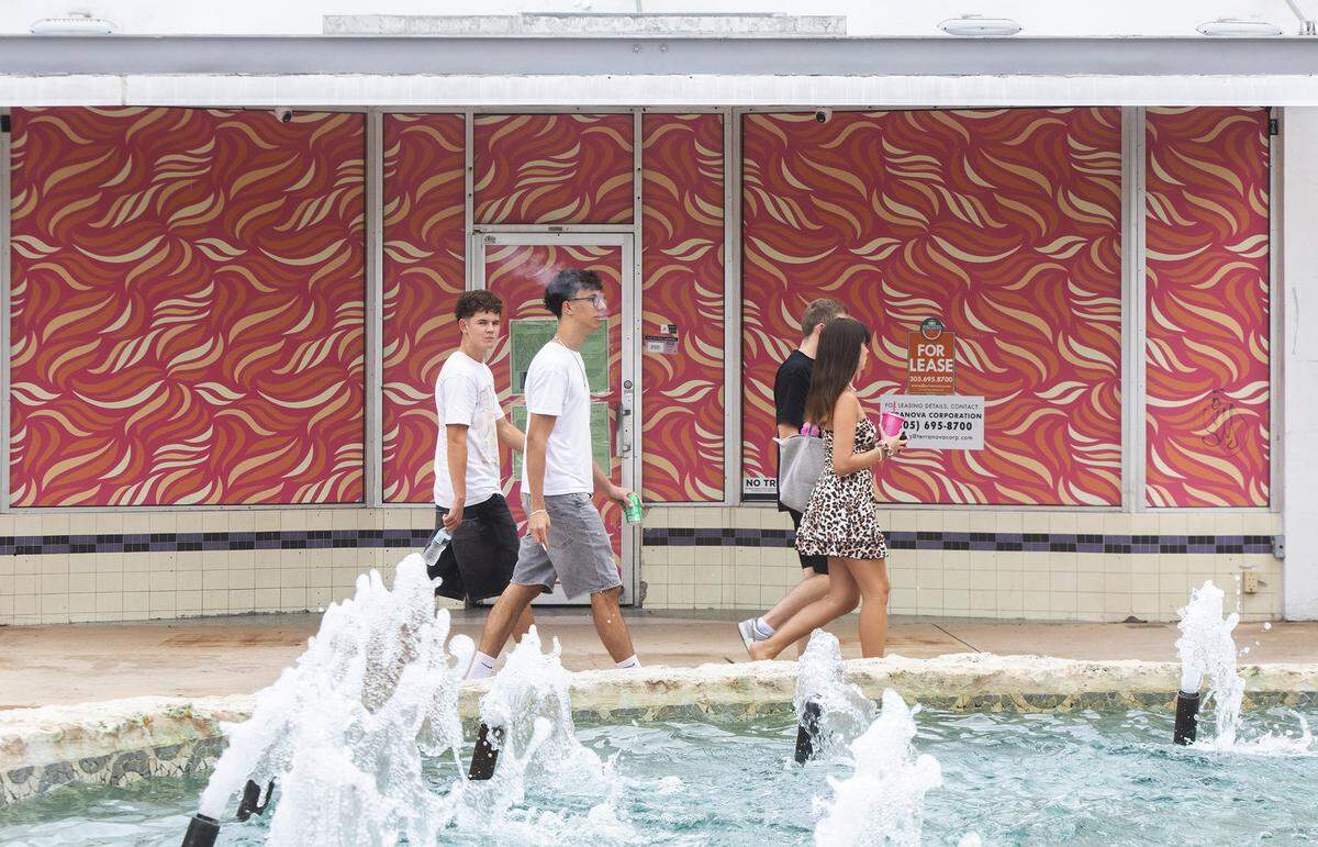 People walk past a vacant store on Miami Beach’s Lincoln Road Mall, which has seen a downturn in recent years. A long-delayed renovation of the pedestrian street now under way will restore worn water features like the fountain in the foreground.