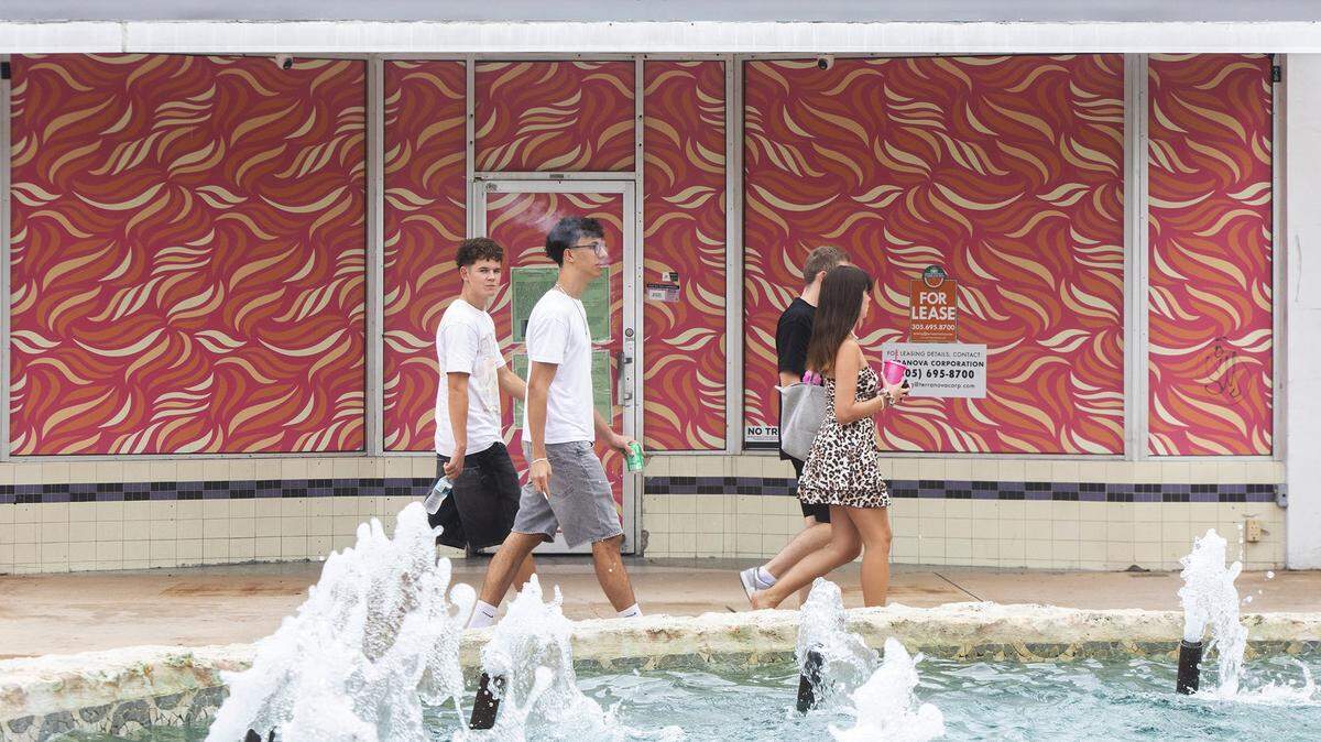 People walk past a vacant store on Miami Beach’s Lincoln Road Mall, which has seen a downturn in recent years. A long-delayed renovation of the pedestrian street now under way will restore worn water features like the fountain in the foreground.