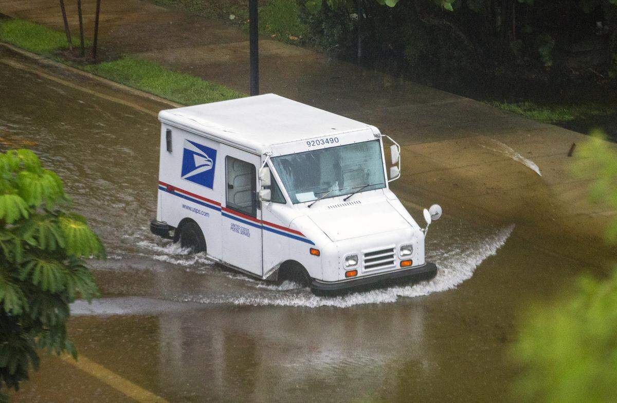 A United States Postal Service mail truck goes through floodwaters caused by heavy rains at North Bay Road and 180th Drive in Sunny Isles Beach on Monday, May 25, 2020.