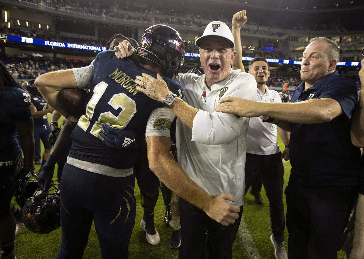 FIU Panthers head coach Butch Davis hugs FIU Panthers quarterback James Morgan (12) after the Panthers defeat the Miami Hurricanes at Marlins Park on Saturday, November 23, 2019.
