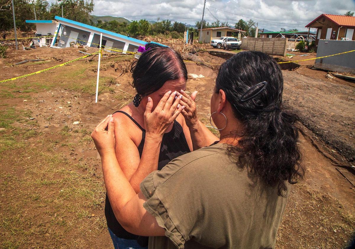 Doris Romero (derecha) consuela a su vecina Leida Rodríguez, cuya casa se derrumbó en un socavón  tras la inundación del río Nigua durante el huracán Fiona en Villa Esperanza en Salinas, Puerto Rico.