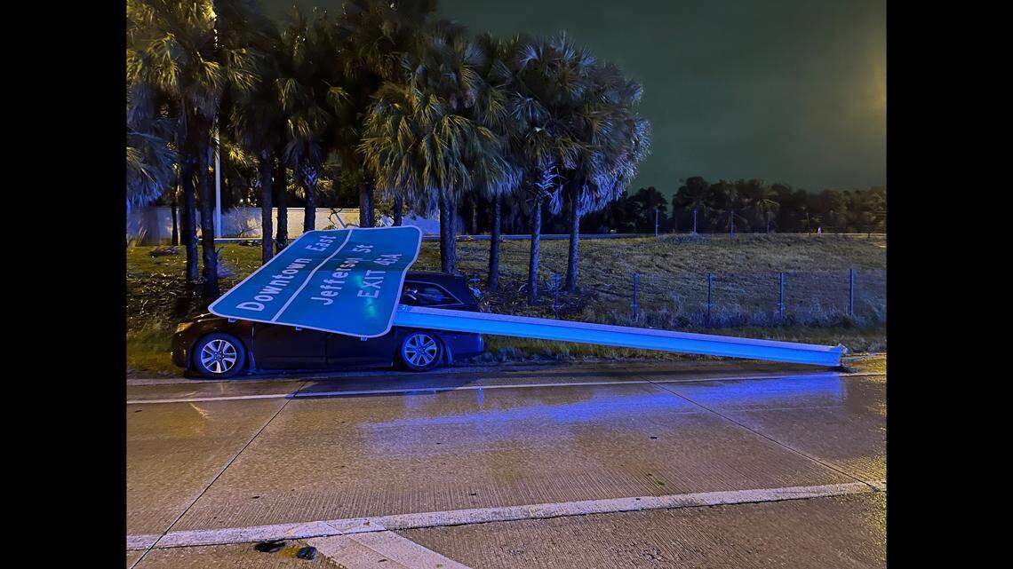 The car had four people in it when the sign came tumbling down and smacked into the roof around 7:50 p.m., officials said.