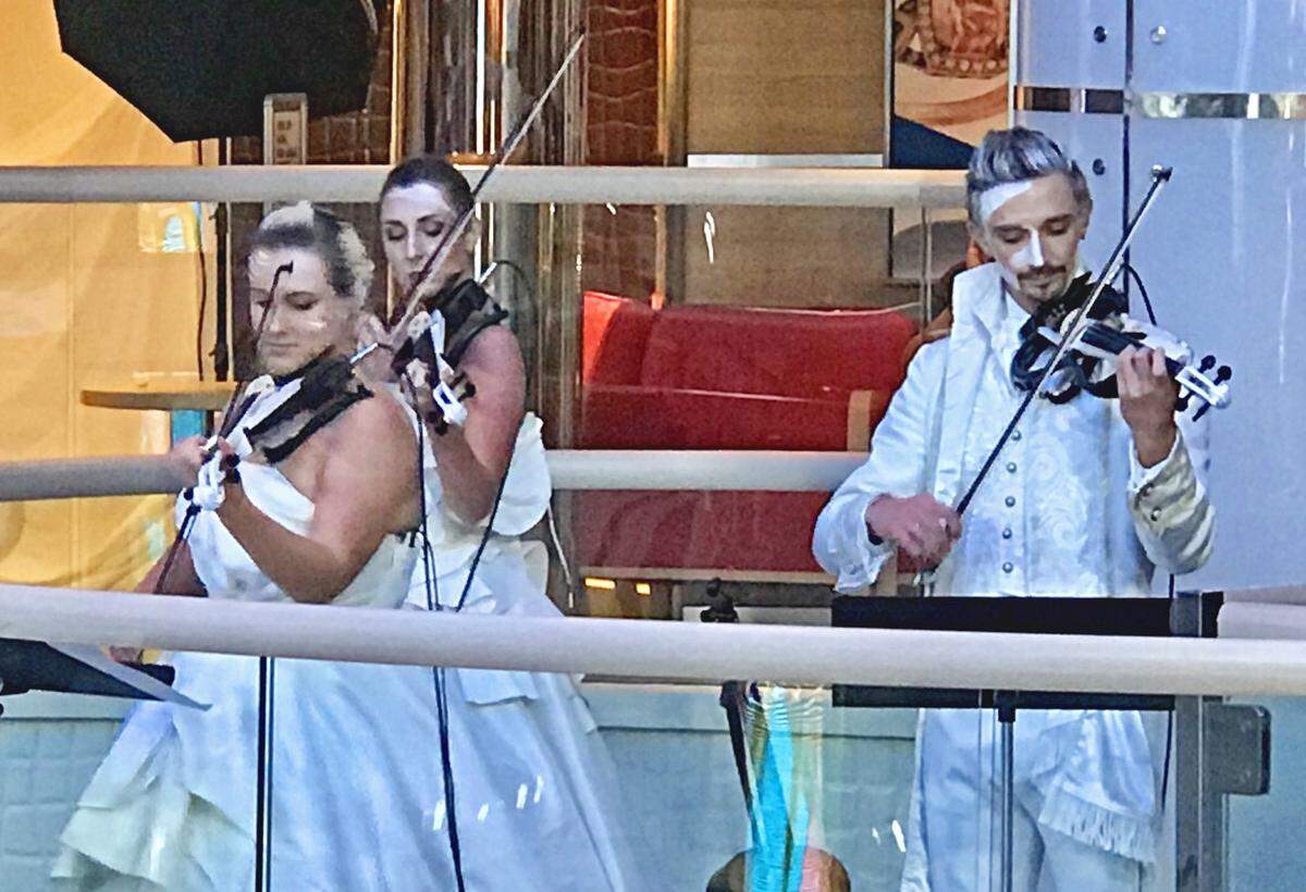 On a landing above the Atrium Bar, musician give passengers on the Carnival Horizon a preview of their stage show, “Celestial Strings.”