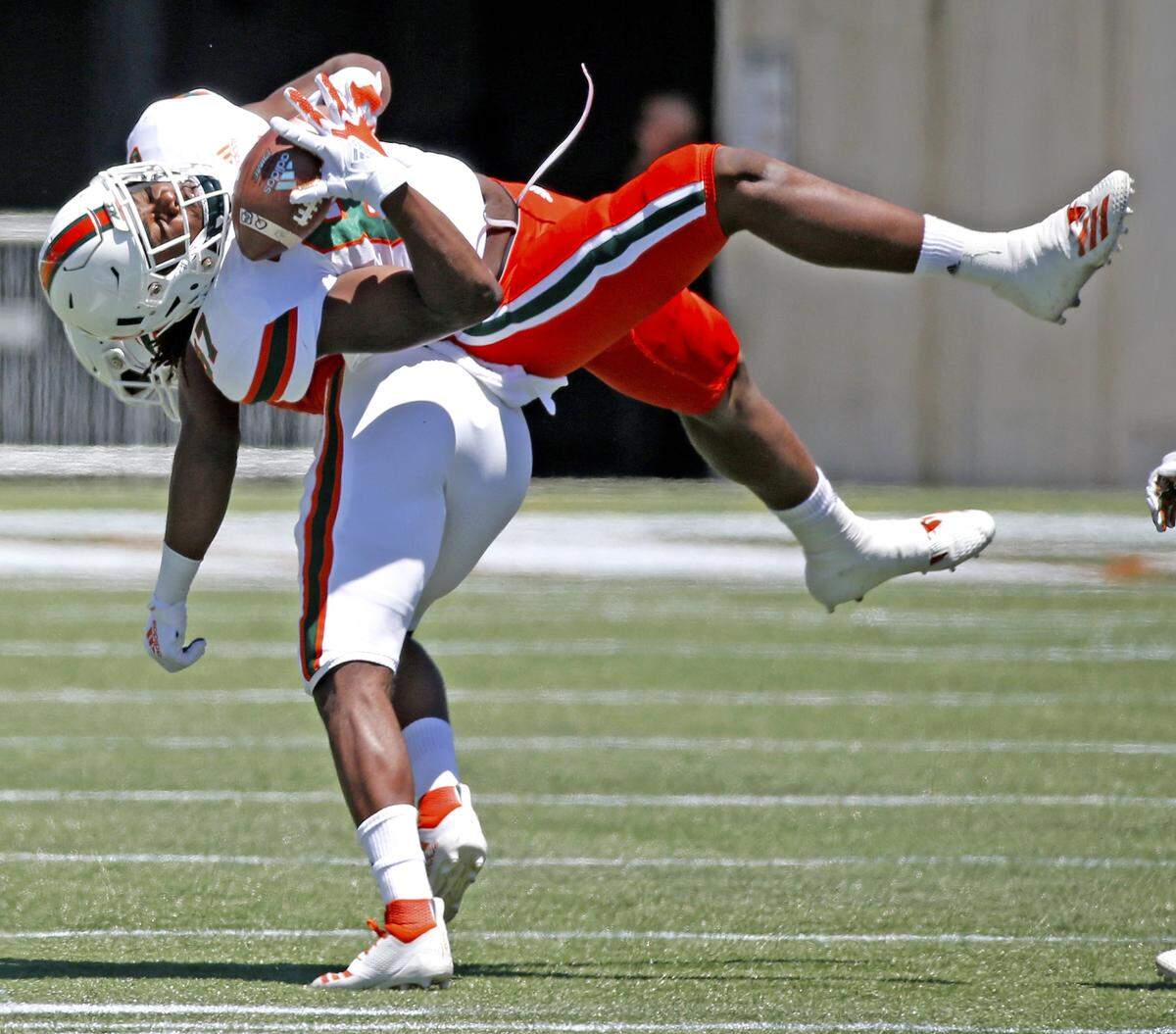 Miami Hurricanes tight end Michael Irvin II (87) hangs onto the ball after getting upended by Canes defensive back Al Blades Jr. (7) during the spring game at Camping World Stadium in Orlando on Saturday, April 20, 2019.