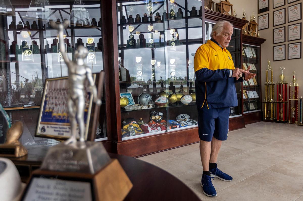 Fort Lauderdale, Florida, June 2, 2021 -Surrounded by trophies won by St. Thomas Aquinas sports teams, George Smith, Athletic Director at St. Thomas Aquinas High School in Fort Lauderdale gestures as he talks to a Miami Herald reporter during an interview. George Smith, one of the most storied coaches in high school football history, is retiring at the end of the school year.