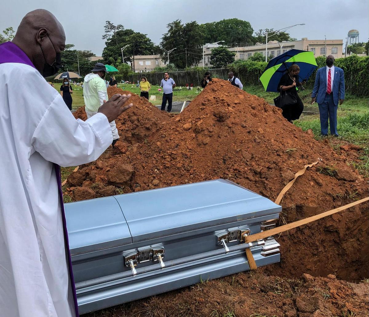En San Juan, Puerto Rico, el padre Olin Pierre Louis da su última bendición a una mujer haitiana que murió el mes pasado al volcar la embarcación sobrecargada en la que viajaba. El funeral y el entierro tuvieron lugar el miércoles 15 de junio de 2022.