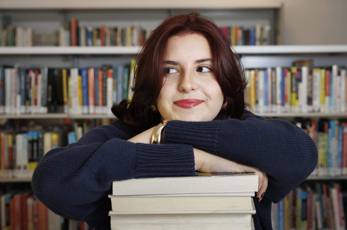 Liz Aronson poses with books on Thursday, Aug. 7, 2025, at the Miami-Dade Doral Branch Library in Doral, Fla.  Aronson is doing community service with the World Literacy Foundation this summer. 