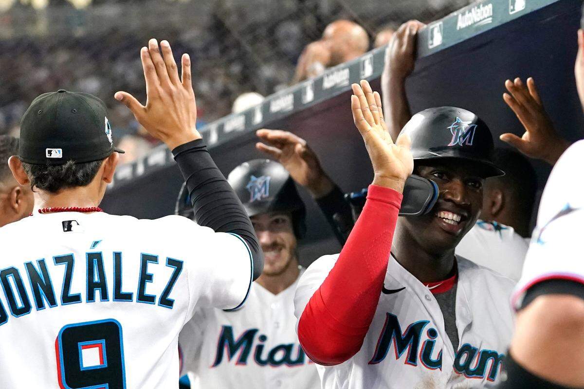 Miami Marlins’ Jesus Sanchez, right, and Brian Anderson, center, are congratulated after scoring on a home run by Anderson during the fourth inning of the team’s baseball game against the Milwaukee Brewers, Saturday, May 14, 2022, in Miami. (AP Photo/Lynne Sladky)