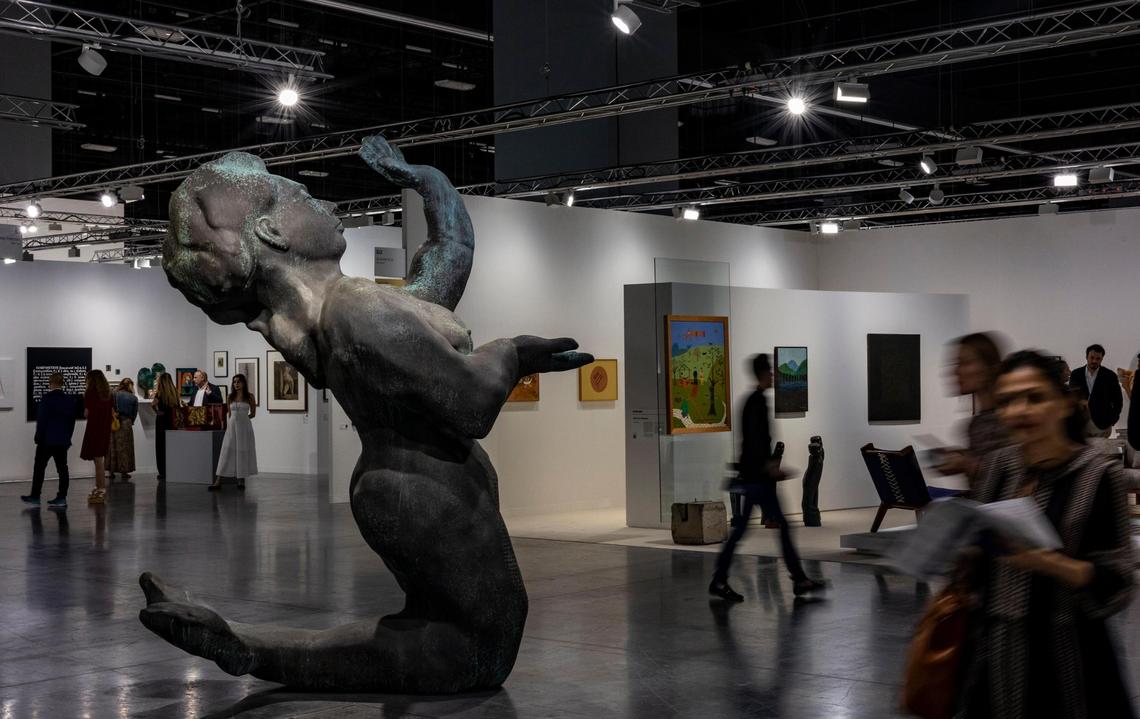 People walk past a cast bronze sculpture entitled “Nixe” by Thomas Schütte at the Art Basel VIP opening day in Miami Beach.