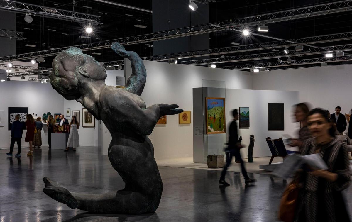 People walk past a cast bronze sculpture entitled “Nixe” by Thomas Schütte at the Art Basel VIP opening day in Miami Beach.