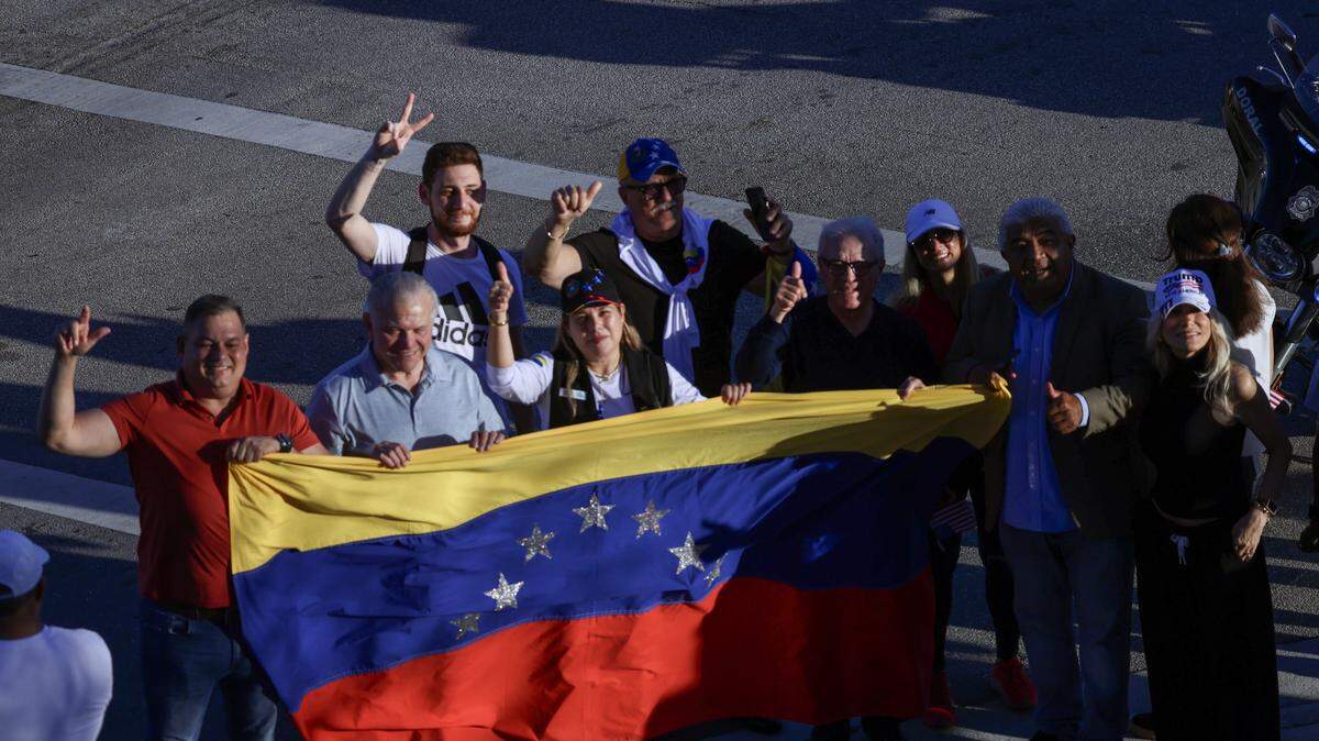 A small group of Venezuelan stretch a Venezuelan flag while waiting for President Donald Trump arrival as he visited El Arepazo, a Venezuelan community hub in Doral, for a brief four-minute stop, greeting Republican guests invited to the restaurant on Monday, March 9, 2026, in Doral, Florida.