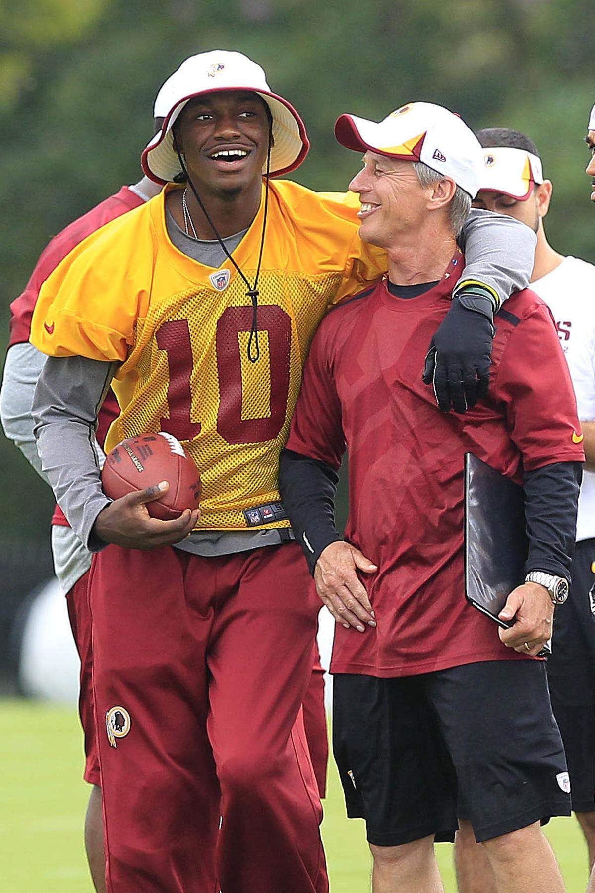 Aug 13, 2013; Richmond, VA, USA; Washington Redskins quarterback Robert Griffin III (10) jokes with Redskins linebackers coach Bob Slowik (right) prior to a morning walkthrough as part of the 2013 NFL training camp at the Bon Secours Washington Redskins Training Center. Mandatory Credit: Geoff Burke-USA TODAY Sports