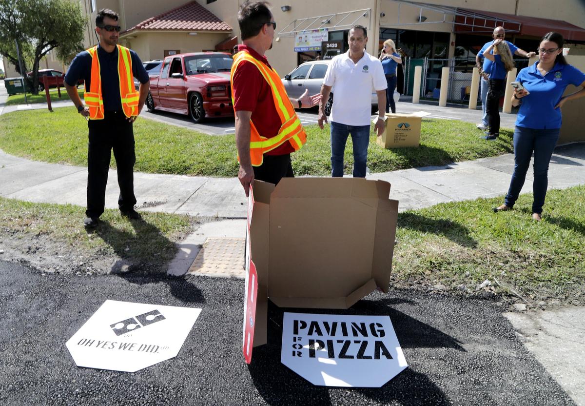 When Domino’s Pizza gave $5,000 to fix potholes on county roads in the Kendall area, it sent along stencils for adding its logo to the pavement. County workers used spray paint to put the Domino’s logo and slogan on the asphalt over the first fixed pothole, but the dozens of other potholes set to be repaired with the grant money won’t be carrying marketing images.