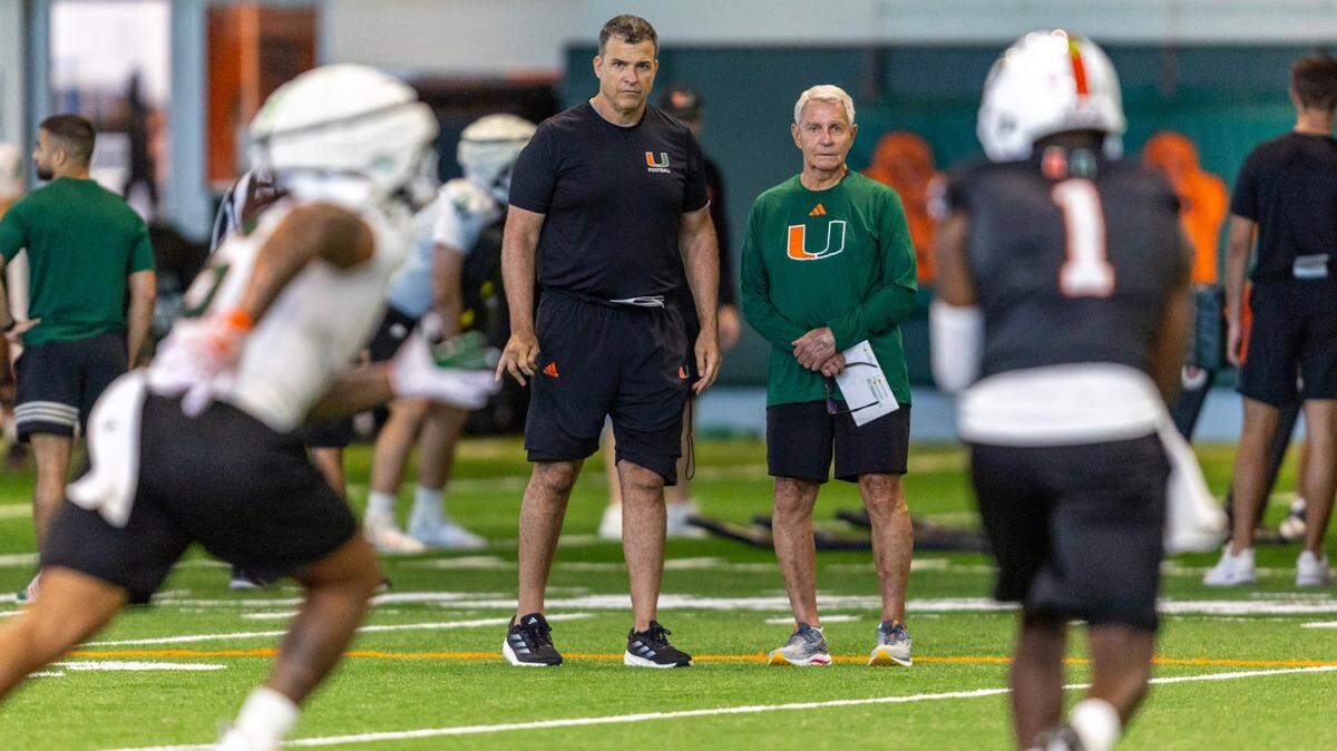 Miami Hurricanes Head Coach Mario Cristobal watches quarterback Cam Ward (1) run through practice drills at the Carol Soffer Indoor Practice Facility on Thursday, August 1, 2024, in Coral Gables, Fla.