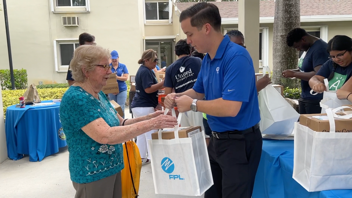 File photo of FPL External Affairs Manager Chris Ferreira handing a hurricane meal kit to a Miami-Dade senior.