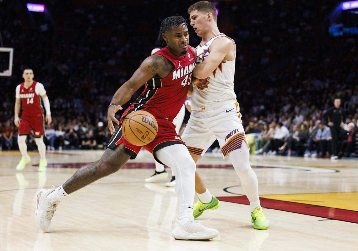 Miami Heat guard Davion Mitchell (45) drives passed Phoenix Suns guard Collin Gillespie (12) during the first half of a game on Jan. 13, 2026, at Kaseya Center in Miami.