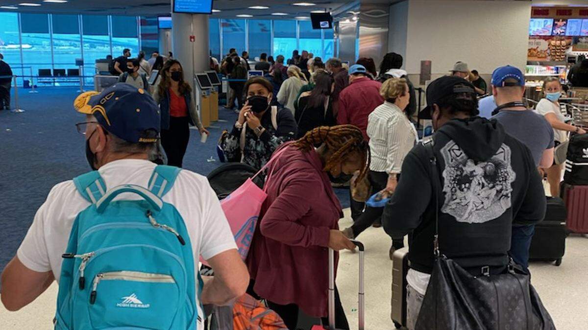People stand in a rebooking line at the American Airlines terminal in Miami International Airport Friday, April 1, 2022. Airport officials say stormy weather Thursday and Friday caused flight cancellations and backups.
