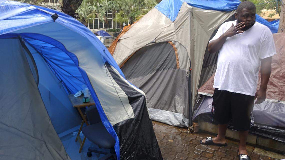 Demetrius Lewis looks over his flooded out tent at the homeless encampment where he lives in front of the Broward County Main Library in Fort Lauderdale.
