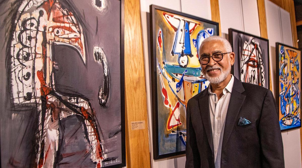 El renombrado artista haitiano Philippe Dodard posa junto a algunas de sus obras recientes durante la recepción de la Exposición de Bellas Artes y Premios del Caribe 2022 para celebrar el 19º aniversario de la organización social y cultural haitiana Le P'ti Club, donde recibió un premio a la trayectoria, en Plantation, el viernes 16 de septiembre de 2022.