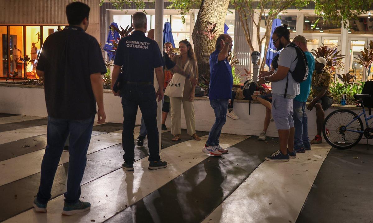 The canvassing team pauses as Ron Book, center, engages in conversation during the count of the unsheltered population on Thursday, Aug. 22, 2024, in Miami Beach, Florida.