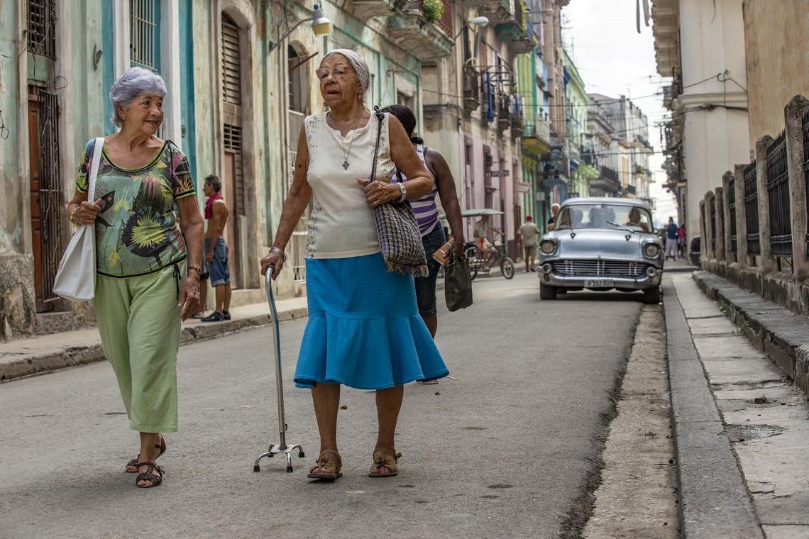 In this file photo, elderly participants in the Circulo de Abuelos program, Yolanda Montane, left, and Juana Aleman, right, walk to Iglesia de Nuestra Señora de la Merced for church services. Montane is now sick and cannot go to the center.