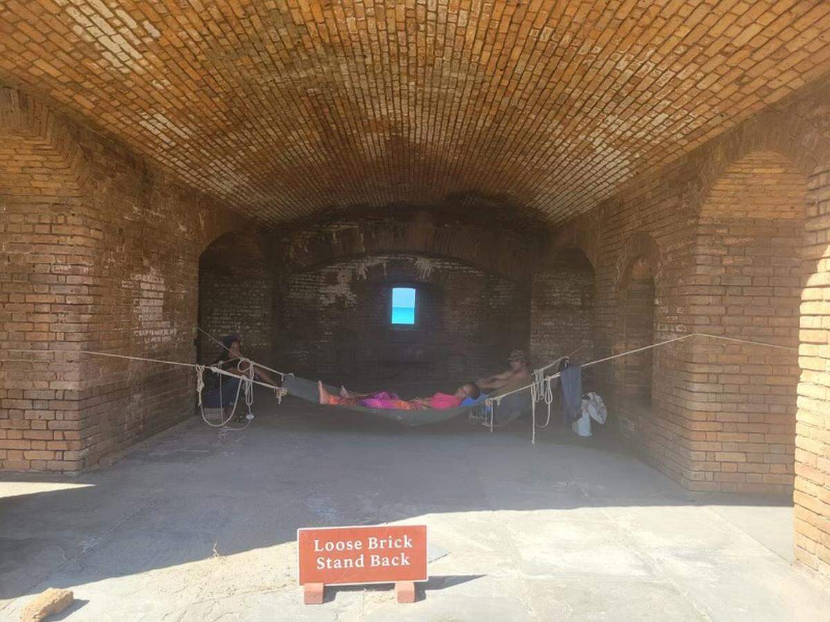 A woman lies in a makeshift hammock hung between two walls at Fort Jefferson in the Dry Tortugas National Park. The National Park Service closed the Tortugas Sunday, Jan. 1, 2022, after almost 500 Cuban migrants arrived there over the course of several days.