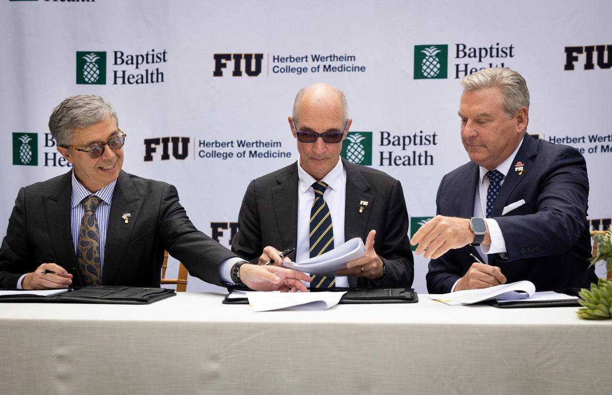 Juan Cendan, decano de la Facultad de Medicina Herbert Wertheim de la FIU, izquierda; Kenneth Jessell, presidente de la FIU, centro, y Bo Boulenger, presidente ejecutivo de Baptist Health South Florida, firman documentos durante una ceremonia para la asociación clínica y académica entre Baptist Health y la Universidad Internacional de la Florida, el martes 28 de noviembre de 2023, en el Baptist Health Miami Cancer Institute.
