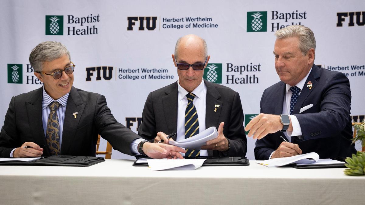 Juan Cendan, Dean of the Herbert Wertheim College of Medicine at FIU, left; Kenneth Jessell, FIU president, center; and Bo Boulenger, CEO of Baptist Health South Florida, sign papers during a ceremony for the clinical and academic partnership between Baptist Health and Florida International University on Tuesday, Nov. 28, 2023, at Baptist Health Miami Cancer Institute.