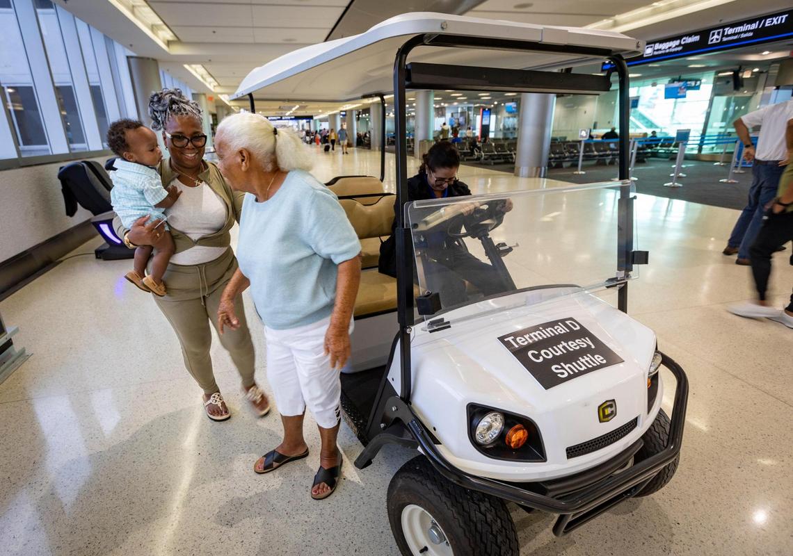 Miami, Florida, September 27, 2023 - Cynthia Swan, center, and her daughter Jacqueline Brennan, carrying her grandson Luca, are dropped off at their gate by the courtesy shuttle in Concourse D at Miami International Airport. The Skytrain is down indefinitely and a courtesy shuttles are the only option passengers have besides walking to get from one end of the terminal to the other.