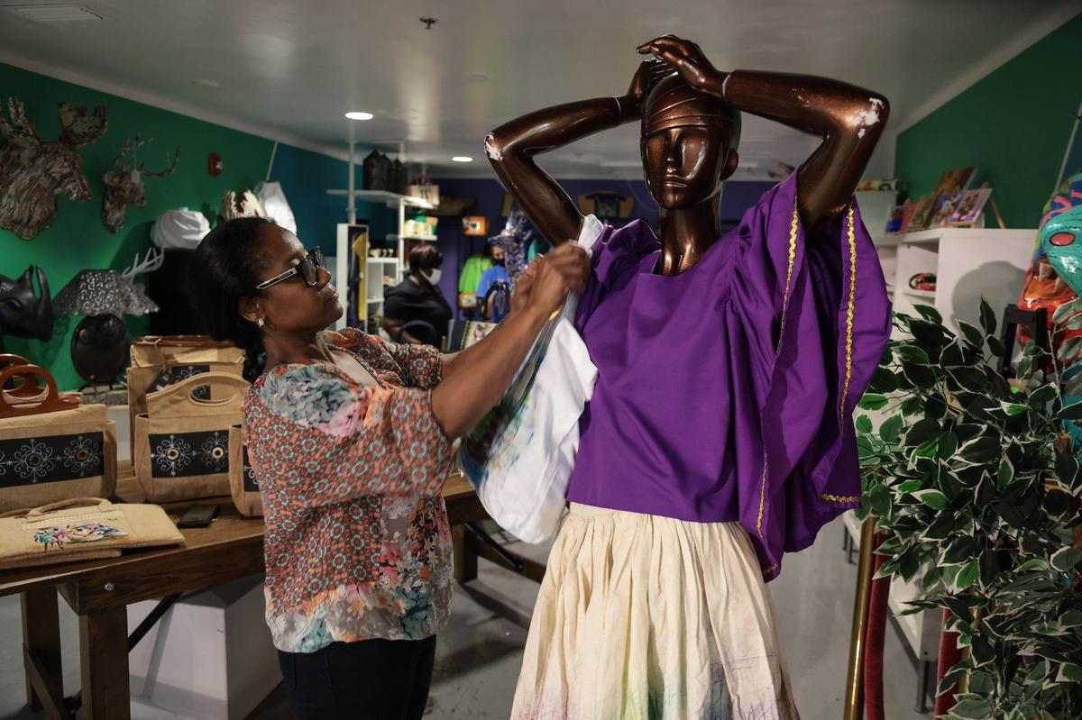 Fashion designer Phelicia Dell dresses up one of the many mannequins displaying her handmade collection called “Veve” at the Little Haiti Cultural Center gift shop, part of the Caribbean Marketplace. Many of the works are created by Haitian artists.