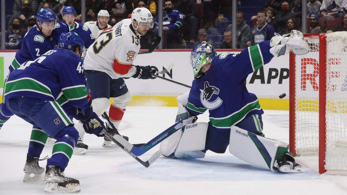 Florida Panthers’ Sam Reinhart (13) has his shot deflect off the post behind Vancouver Canucks goalie Spencer Martin, right, and stay out of the goal during the first period of an NHL hockey game Friday, Jan. 21, 2022, in Vancouver, British Columbia. (Darryl Dyck/The Canadian Press via AP)