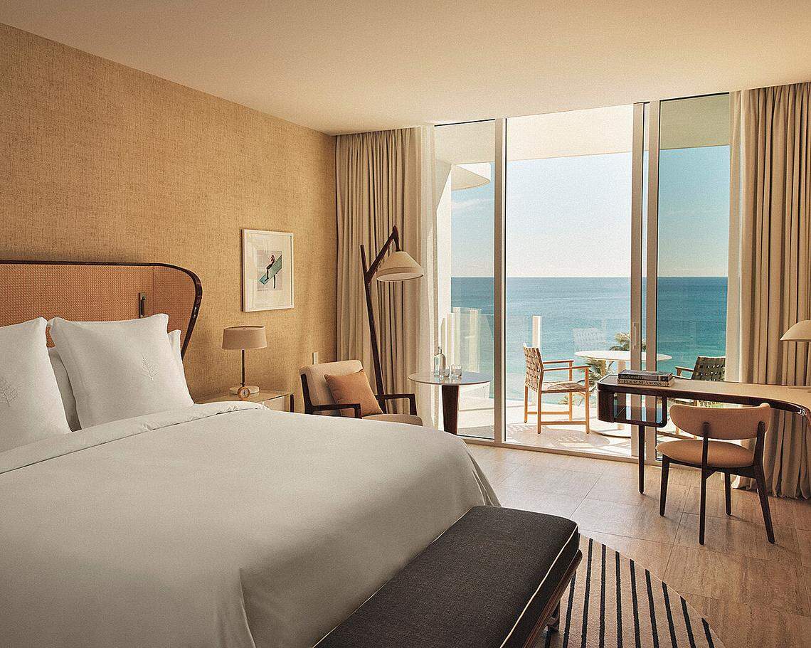 Modern, bright hotel room with queen bed and view of the ocean