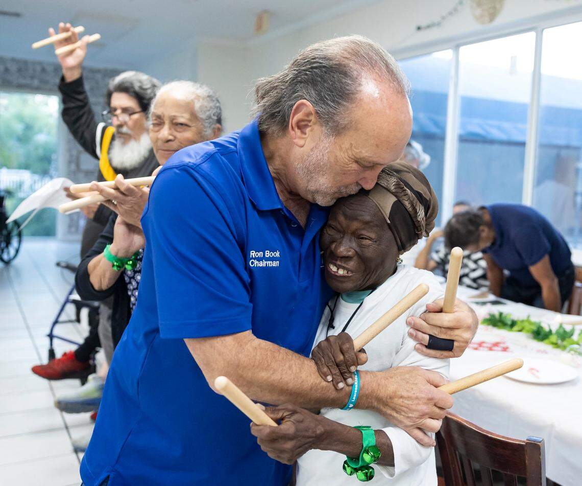 Ron Book, chairman of the Homeless Trust, gives Gisela Tosca, 77, a kiss as they participate in a tree-lighting event for residents at Mia Casa on Thursday, Dec. 19, 2024, in North Miami, Florida. Mia Casa, acquired by Miami-Dade County’s Homeless Trust, supports over 120 homeless seniors aged 65 and older with shelter and assistance transitioning to permanent housing.