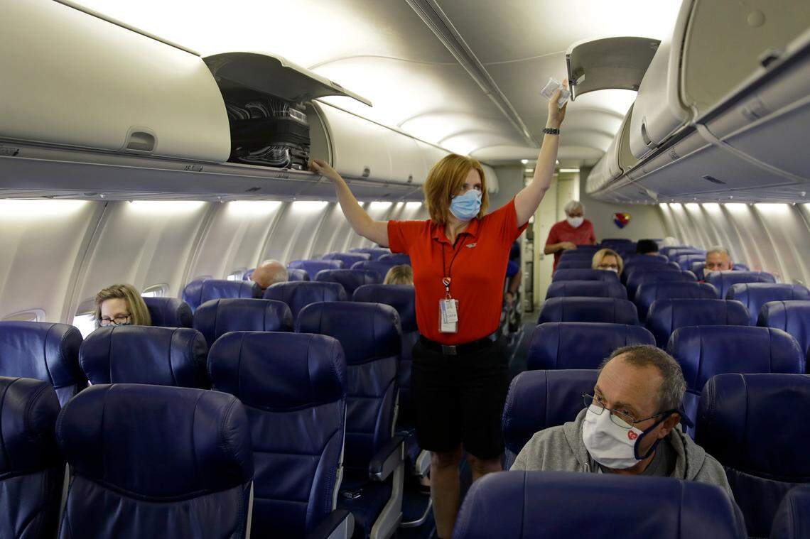 In this May 24, 2020, file photo, a Southwest Airlines flight attendant prepares a plane bound for Orlando, Fla. for takeoff Sunday, at Kansas City International airport in Kansas City, Mo.