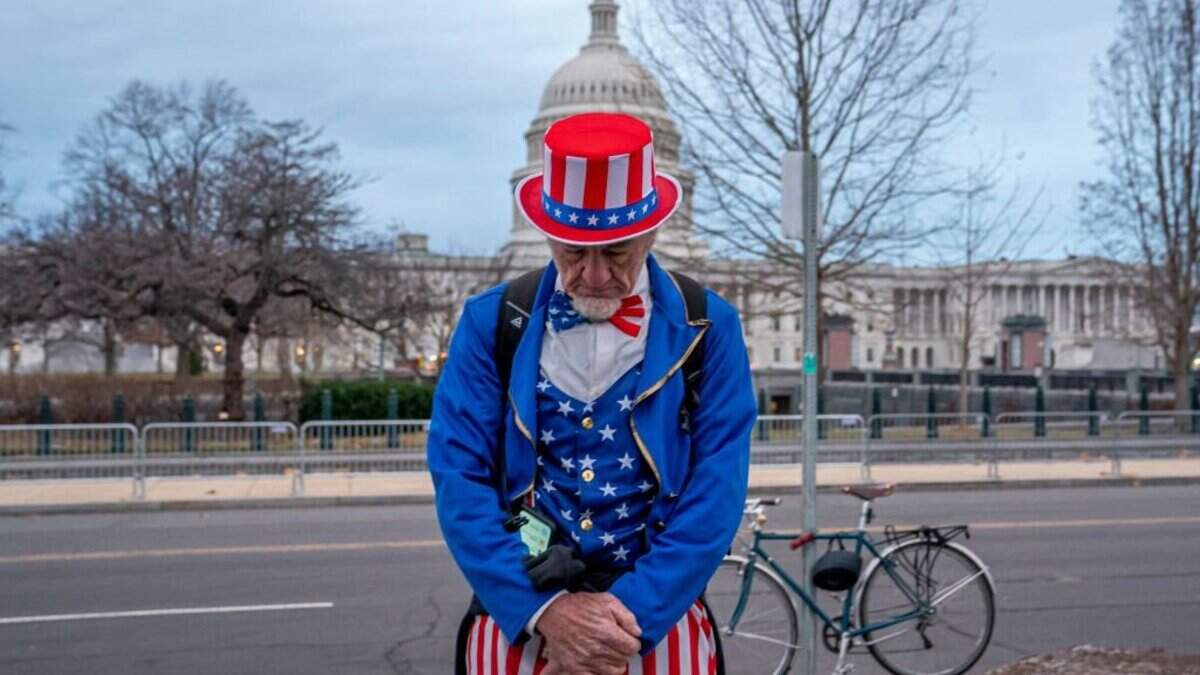WASHINGTON, DC - JANUARY 06: A man dressed as Uncle Sam, whos a regular attendee of events held by former President Donald Trump, stops to pray near community faith leaders during a vigil on the second anniversary of the January 6 attack on the Capitol on January 6, 2023 in Washington, DC. Speakers called for an end to Christian nationalism and denounced political violence. (Photo by Nathan Howard/Getty Images)
