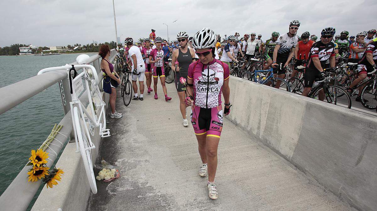 Bicyclists leave flowers at a ghost bike memorial on the Rickenbacker Causeway, where cyclist Christopher Le Canne was killed by a drunken driver.