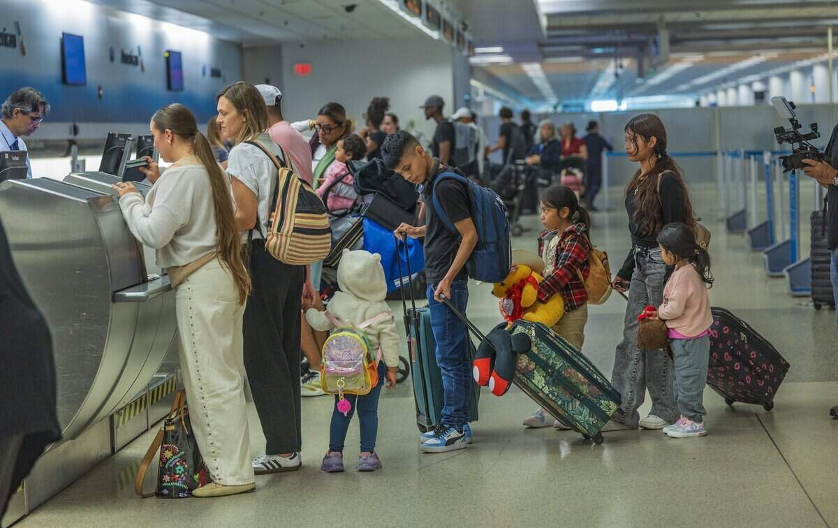 Audra Obando, a volunteer accompanying the children on their flight to Guatemala, holds the hand of Christina, 3, at the American Airlines check-in.