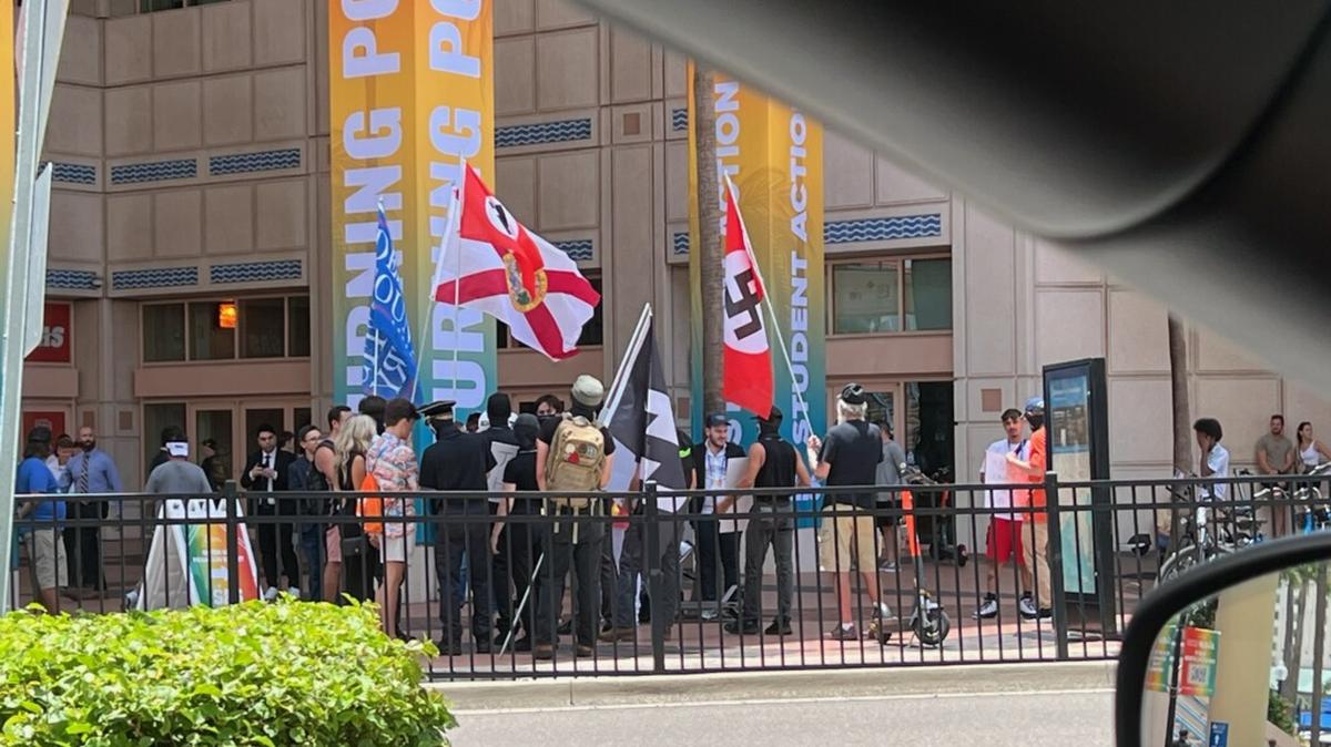 Photos shared by the Florida Holocaust Museum shows men carrying a swastika flag outside the Turning Point USA conference in Tampa. Organizers of the conference said the men pictured were not affiliated with their event.