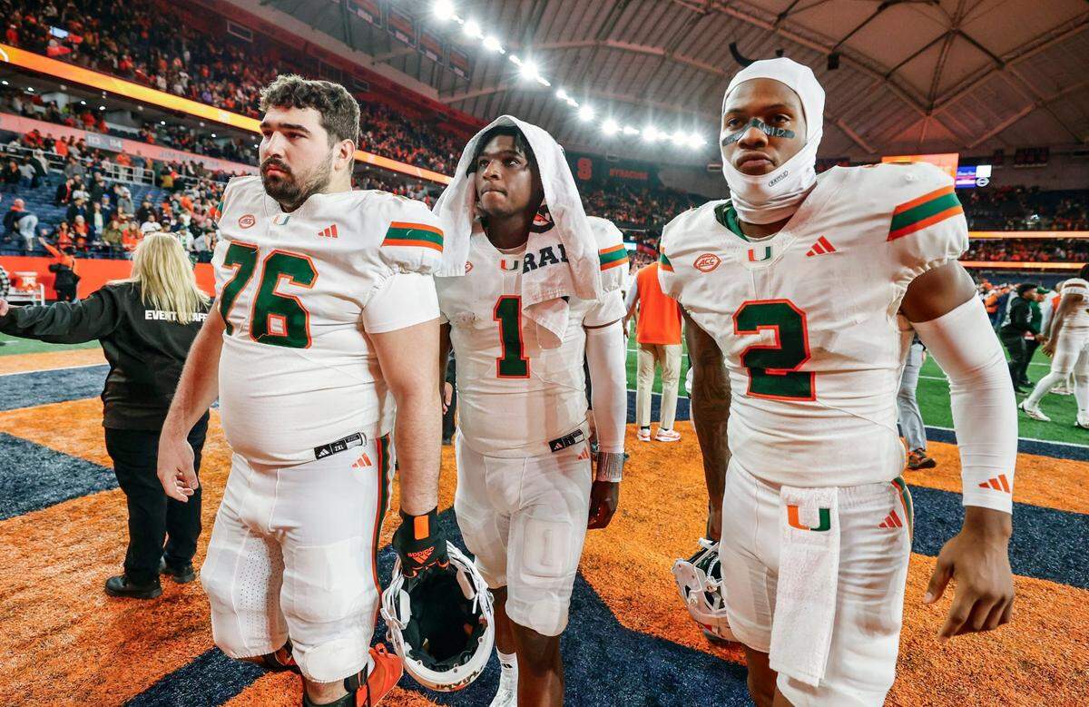 Miami Hurricanes offensive lineman Ryan Rodriguez (76) quarterback Cam Ward (1) and wide receiver Isaiah Horton (2) walk off the field after the Syracuse defeat the Canes 38-42 in their NCAA football game in the JMA Wireless Dome at Syracuse University, Syracuse, New York on Saturday, November 30, 2024.