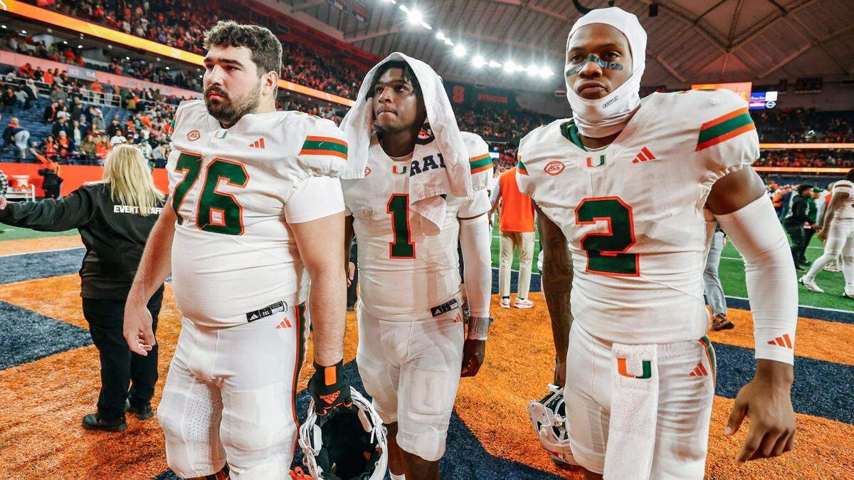 Miami Hurricanes offensive lineman Ryan Rodriguez (76) quarterback Cam Ward (1) and wide receiver Isaiah Horton (2) walk off the field after the Syracuse defeat the Canes 38-42 in their NCAA football game in the JMA Wireless Dome at Syracuse University, Syracuse, New York on Saturday, November 30, 2024.