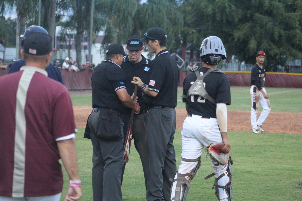 Umpires examine the bat of Taravella’s Matt Rubin during Friday’s Region 4-7A semifinal between the Trojans and Douglas High moments after he drove in a run with an RBI single which was nullified when the bat was found to be illegal.