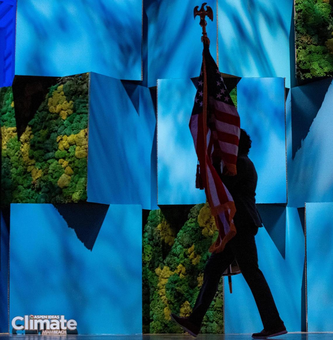 A staff member carries the U.S. flag before the start of a conversation between Gloria Estefan and Vice President Kamala Harris during the Aspen Ideas: Climate conference at the New World Center on Wednesday, March 8, 2023, in Miami Beach, Fla.