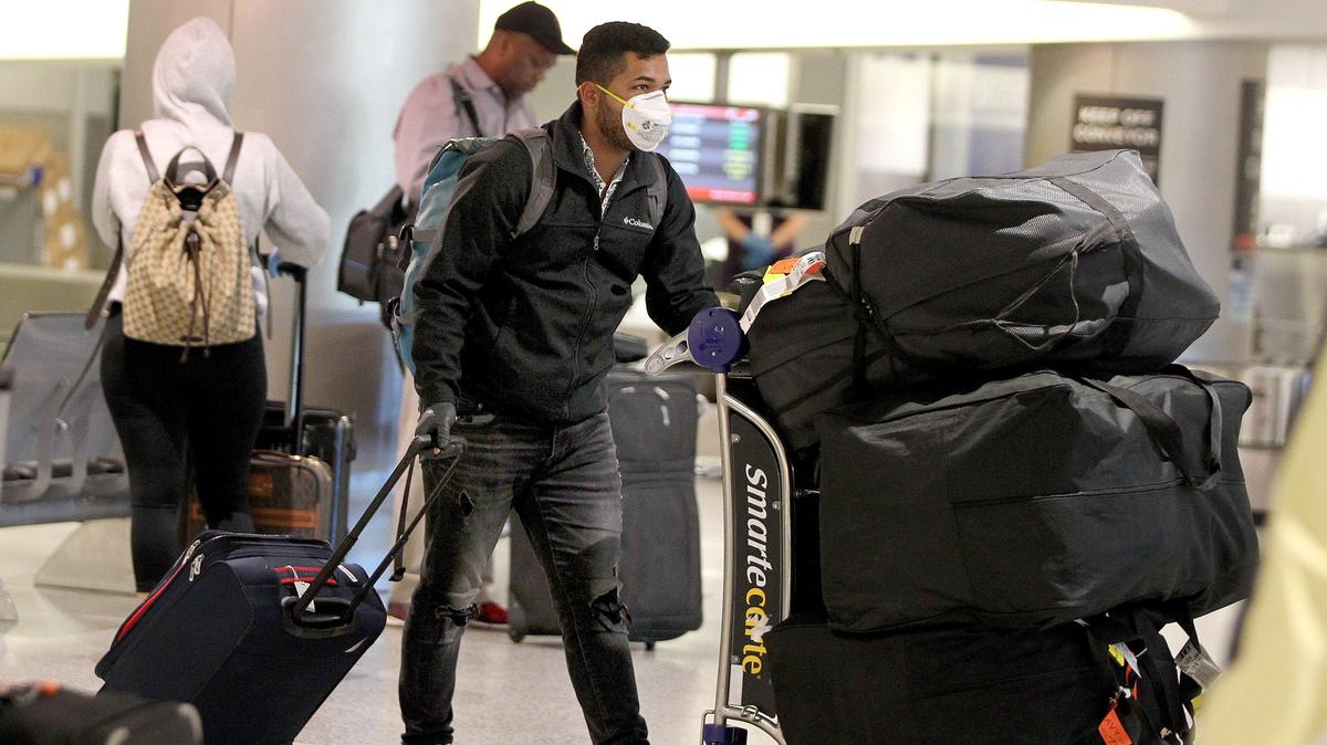 Travelers retrieving bags at Miami International Airport wear masks as protection against the coronavirus on March 24, 2020. On Aug. 6, Gov. Ron DeSantis lifted restrictions on travelers from New York, New Jersey and Connecticut put in place March 23. They no longer have to self-quarantine for two weeks after entering Florida.