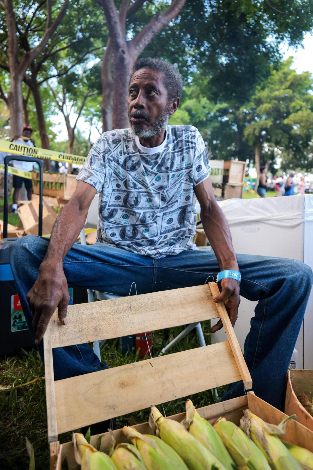 Hansy opens a box with ears of corn on the cob to be peeled, roasted and sold during the 19th annual Best of the Best International Music Festival at Bayfront Park in downtown Miami, Sunday, May 25, 2025. In addition the dancehall artists, the festival featured Caribbean vendors and food.