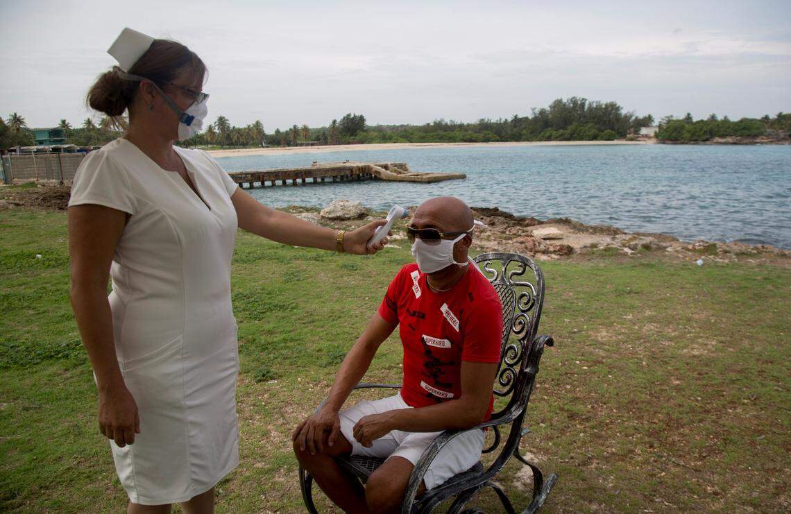 Nurse Leydania Lamela checks the temperature of Italian Roberto Brundu, who has been trapped on the island after the government closed Cuba’s airspace in April as a measure to curb the spread of the new coronavirus. They are shown at Villa Bacuranao in Havana on Wednesday, June 3, 2020.