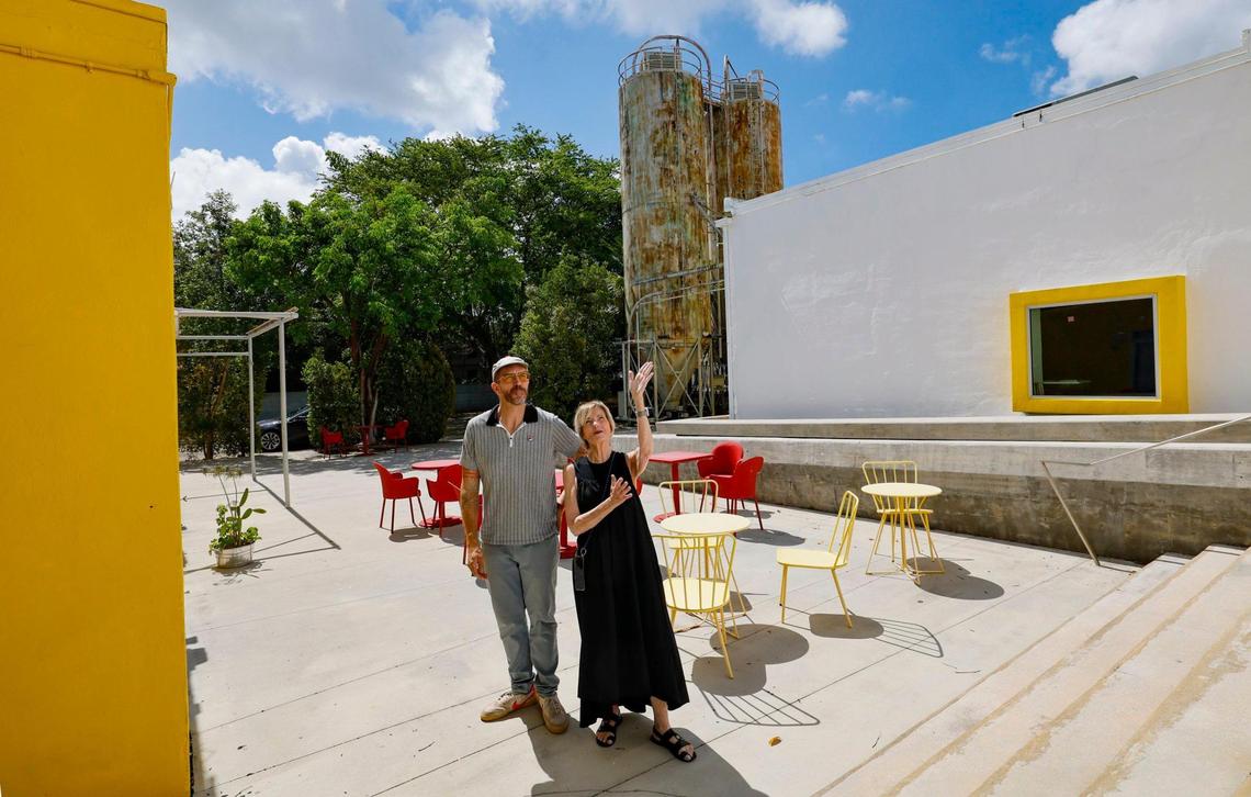 Bakehouse Art Center director Cathy Leff and artist Philip Lique, its technology strategist and planner, stand at the main entrance to the Wynwood complex, housed in a former industrial bakery from 1926. Two surviving flour silos are in the background.