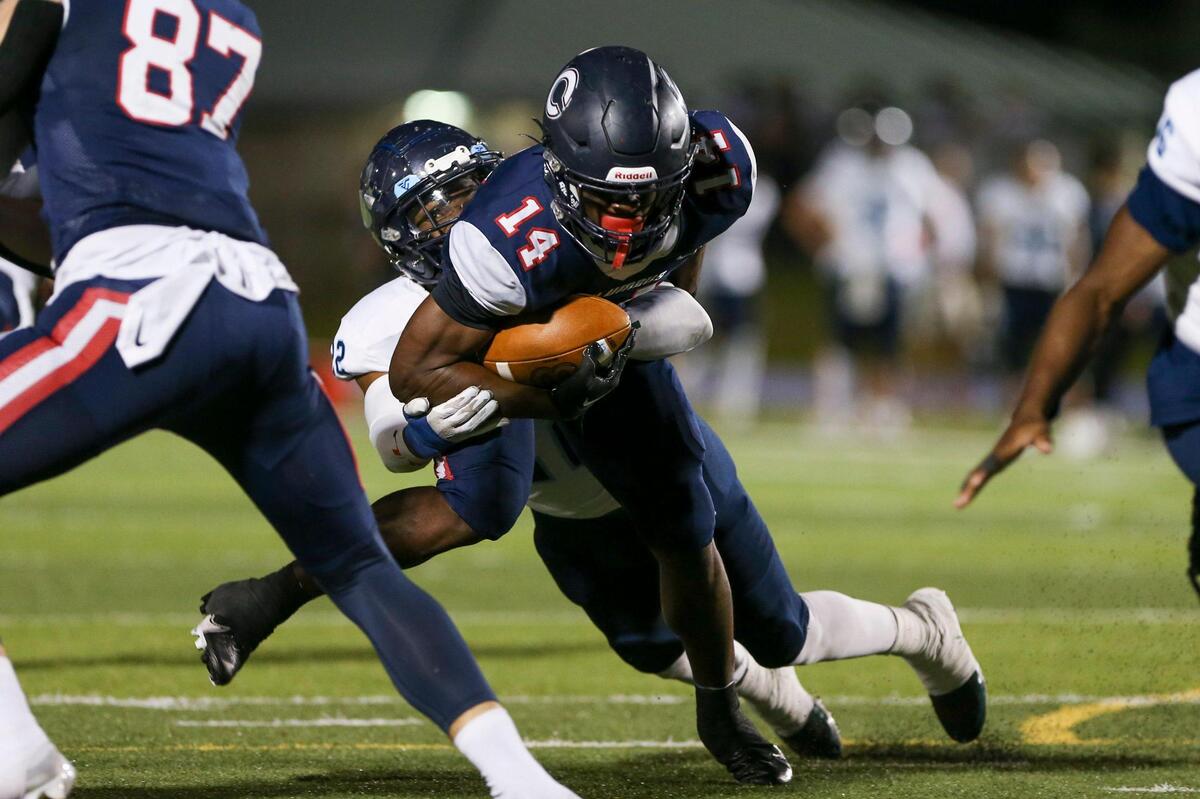 Columbus Explorers running back Sedrick Irvin (14) runs with the football as Palmetto Panthers outside linebacker Bobby Washington (22) attempts a tackle during the second quarter of a high school football playoff game at Tropical Park in Miami, Florida, Friday, November 18, 2022.