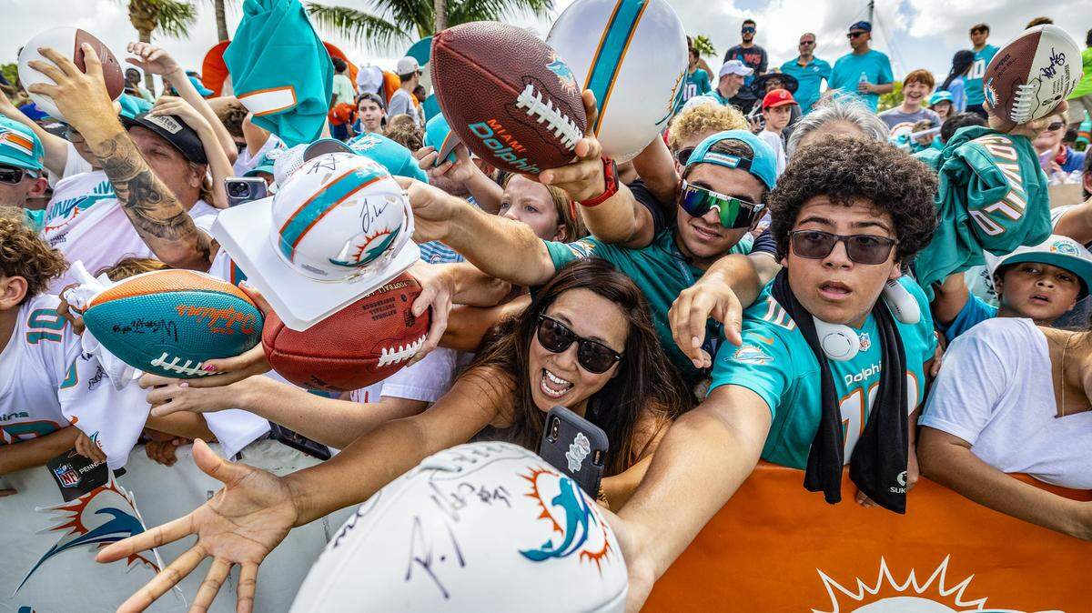 Miami Dolphins fans try to get the attention of football players as they seek autographs after practice at the Miami Dolphins Training Camp in Miami Gardens, Florida.