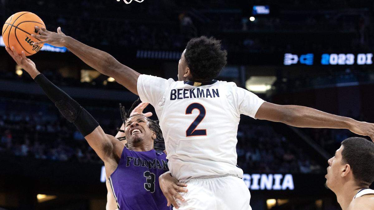 Furman’s Mike Bothwell (1) fights for the ball with Virginia’s Reece Beekman (2) during the first round of the NCAA tournament in Orlando.